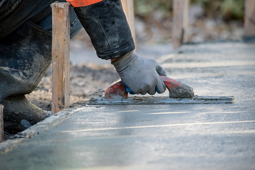 A construction worker is Smoothing wet cement